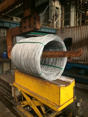Green PET Strapping securing steel wire coils for transport, superior rust-free alternative to metal banding