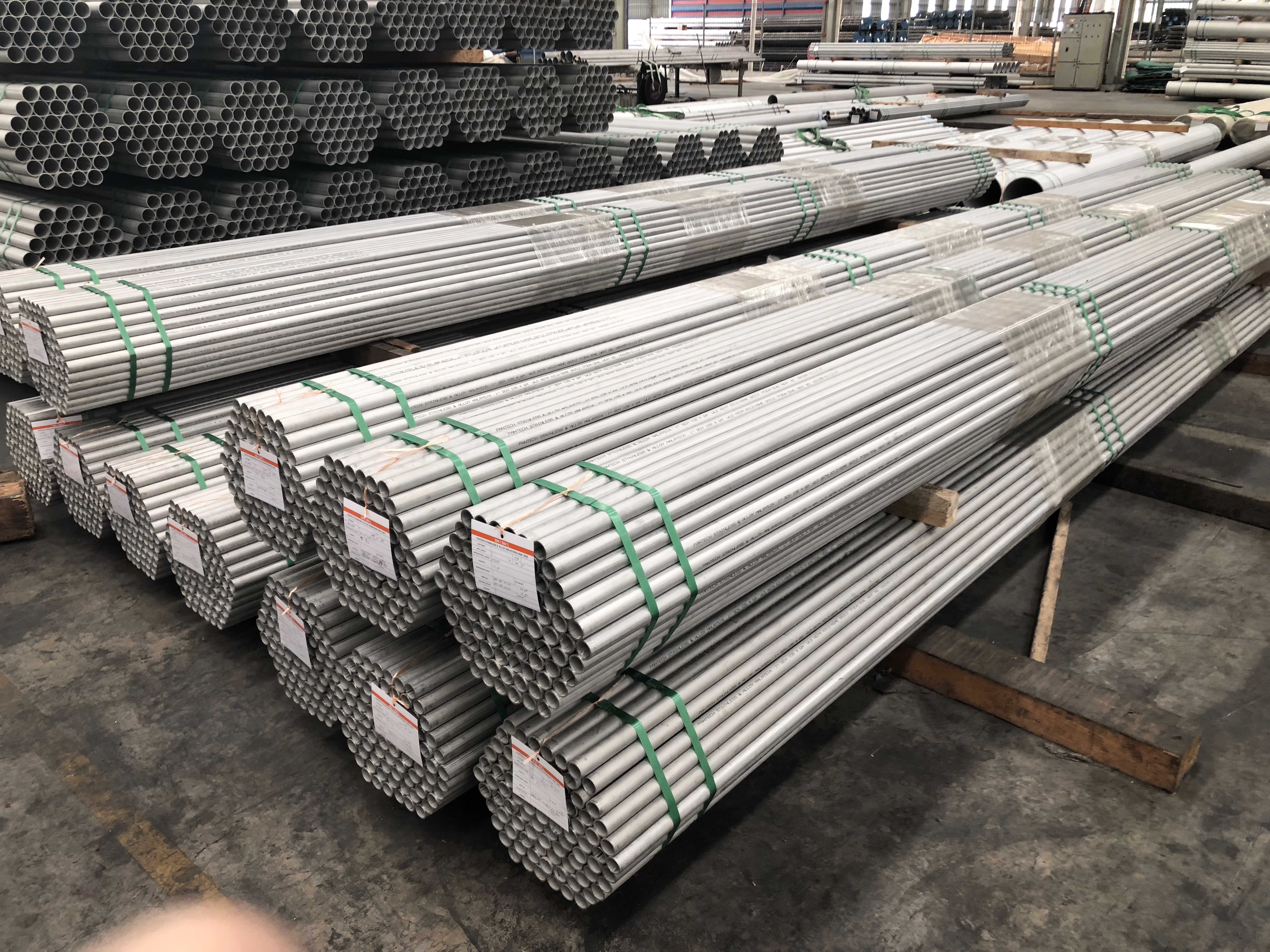 Green PET Strapping securing heavy steel pipes and tubes for stable, high-tension bundling