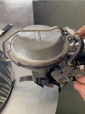 High-tensile industrial steel strapping from Juhong Packing Materials being secured by a FROMM pneumatic strapping tool for heavy-duty load protection.